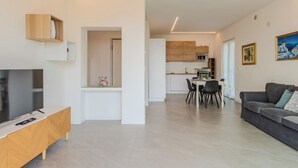 Un salon moderne avec un téléviseur, un canapé et un coin repas.