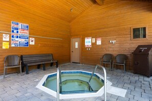 A wooden indoor pool area with a hot tub, benches, and various posted signs. - Shared Hot Tub and Pool | Mountain Views (Mammoth Lakes)