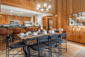 A wooden-paneled kitchen with a dining area set for four. - Shared Hot Tub and Pool | Mountain Views (Mammoth Lakes)