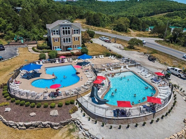 Ein Resort mit mehreren Schwimmbecken, Liegestühlen und einem großen Gebäude.
