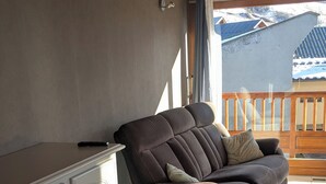 Ein Wohnzimmer mit einer Liegesofa, einem weißen Schrank und Blick auf einen verschneiten Berg.