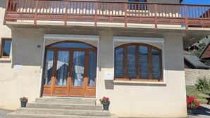 Eine Holzhütte mit Balkon, einem Schild mit der Aufschrift 'Le Colporter' und einem doppeltürigen Eingang.