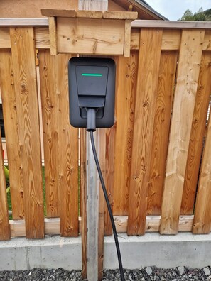 A wooden fence with a charging station mounted on it.