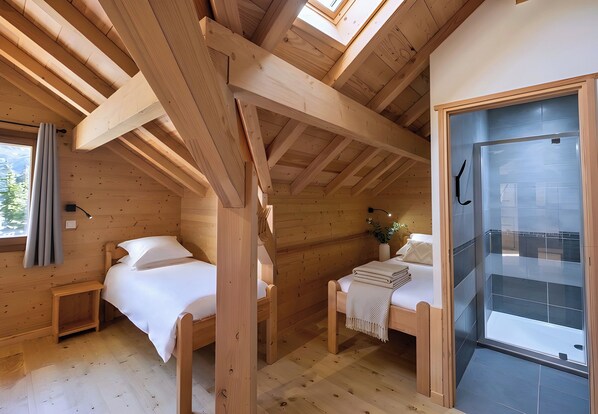 A wooden cabin with two beds, a skylight, and a glass shower enclosure.