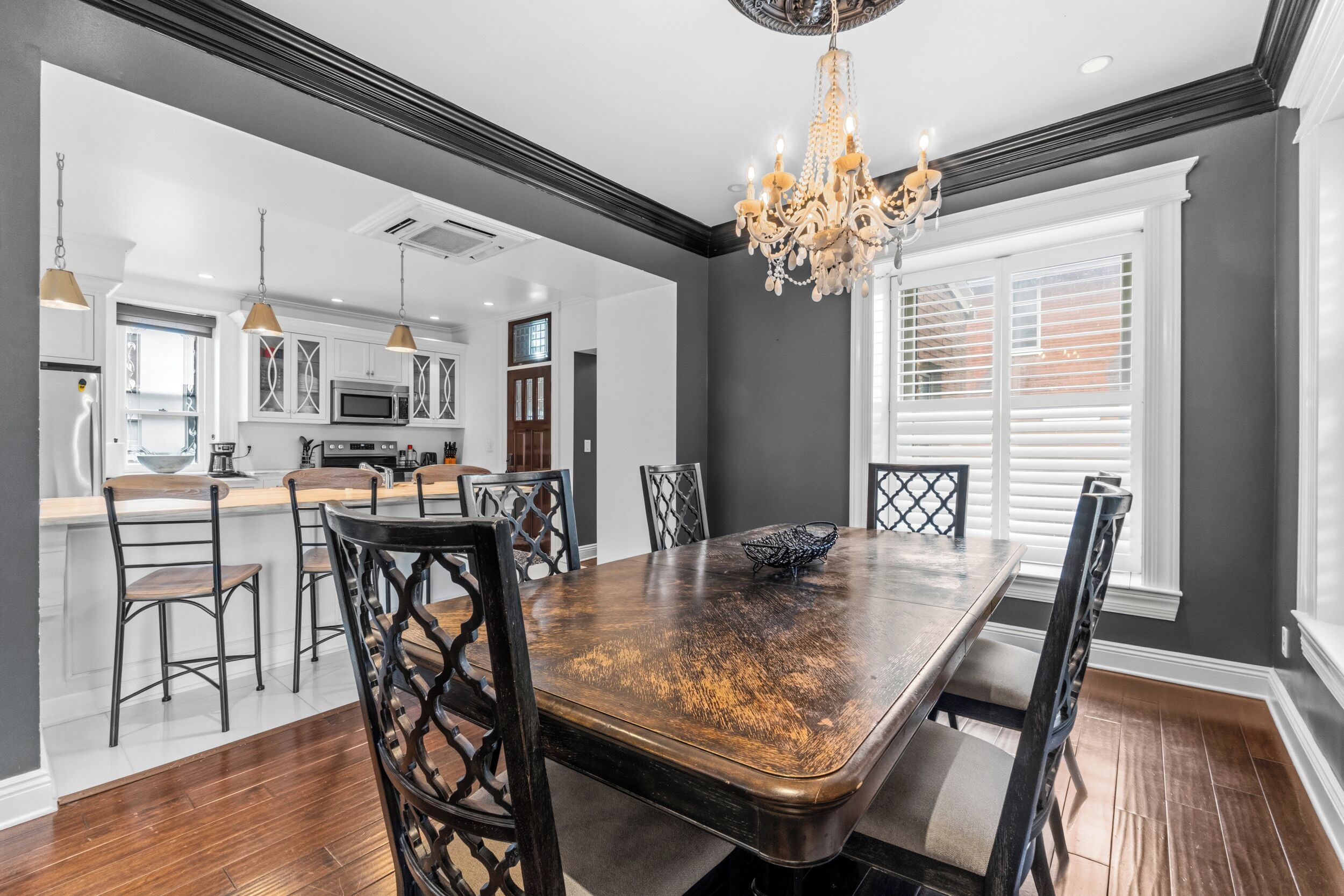 A dining area with a large wooden table, black chairs, and a chandelier.