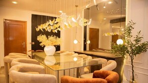 A dining area with a glass table surrounded by chairs, a vase with flowers, and pendant lights. - 3 Bedroom En-Suite, Wi-Fi, Secured, 24/7 Power (Lagos)