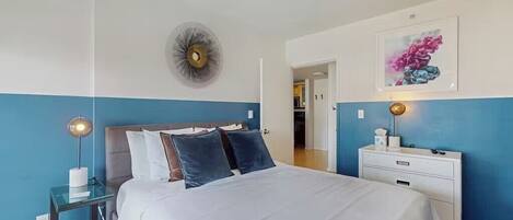 A bedroom with a bed, bedside tables, a wall clock, and a framed picture.