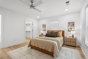 Ein Schlafzimmer mit Bett, Nachttischen, Deckenventilator und Bildern an den Wänden.