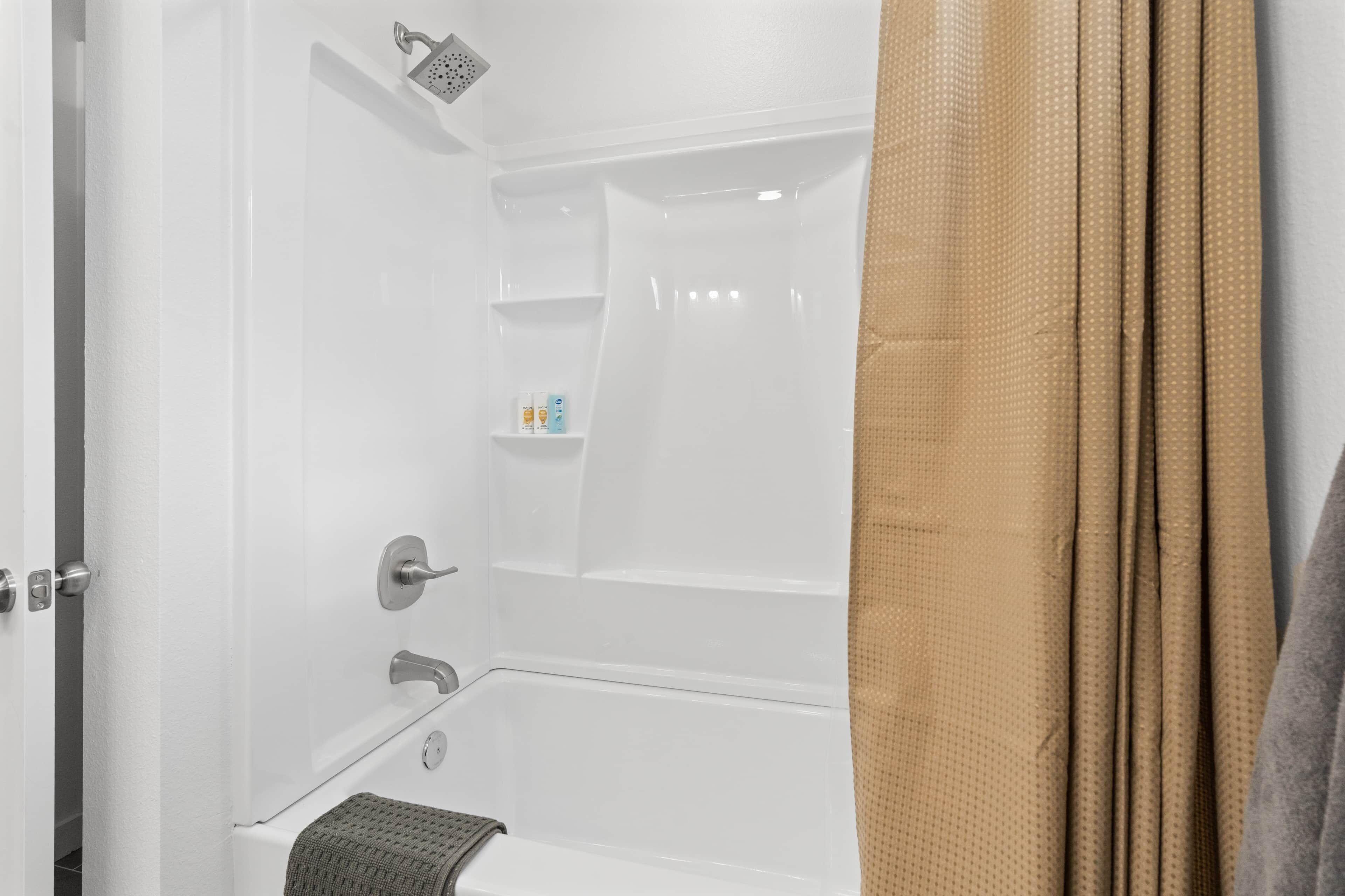 Une salle de bain avec une baignoire, une douche et des toilettes. On y trouve un porte-serviettes sur lequel est accrochée une serviette.