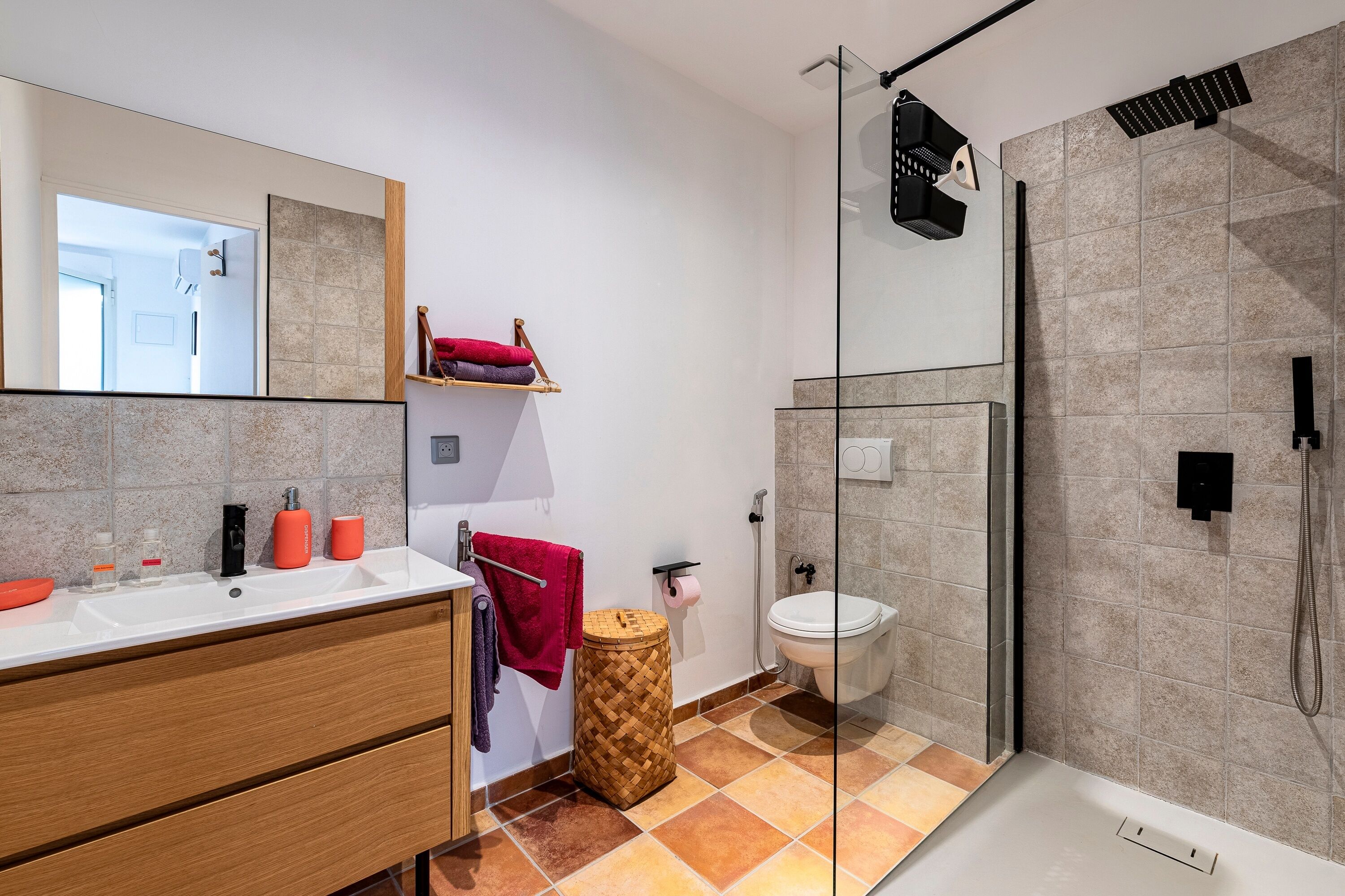 A modern bathroom with a glass shower enclosure, a white sink, and a large mirror.