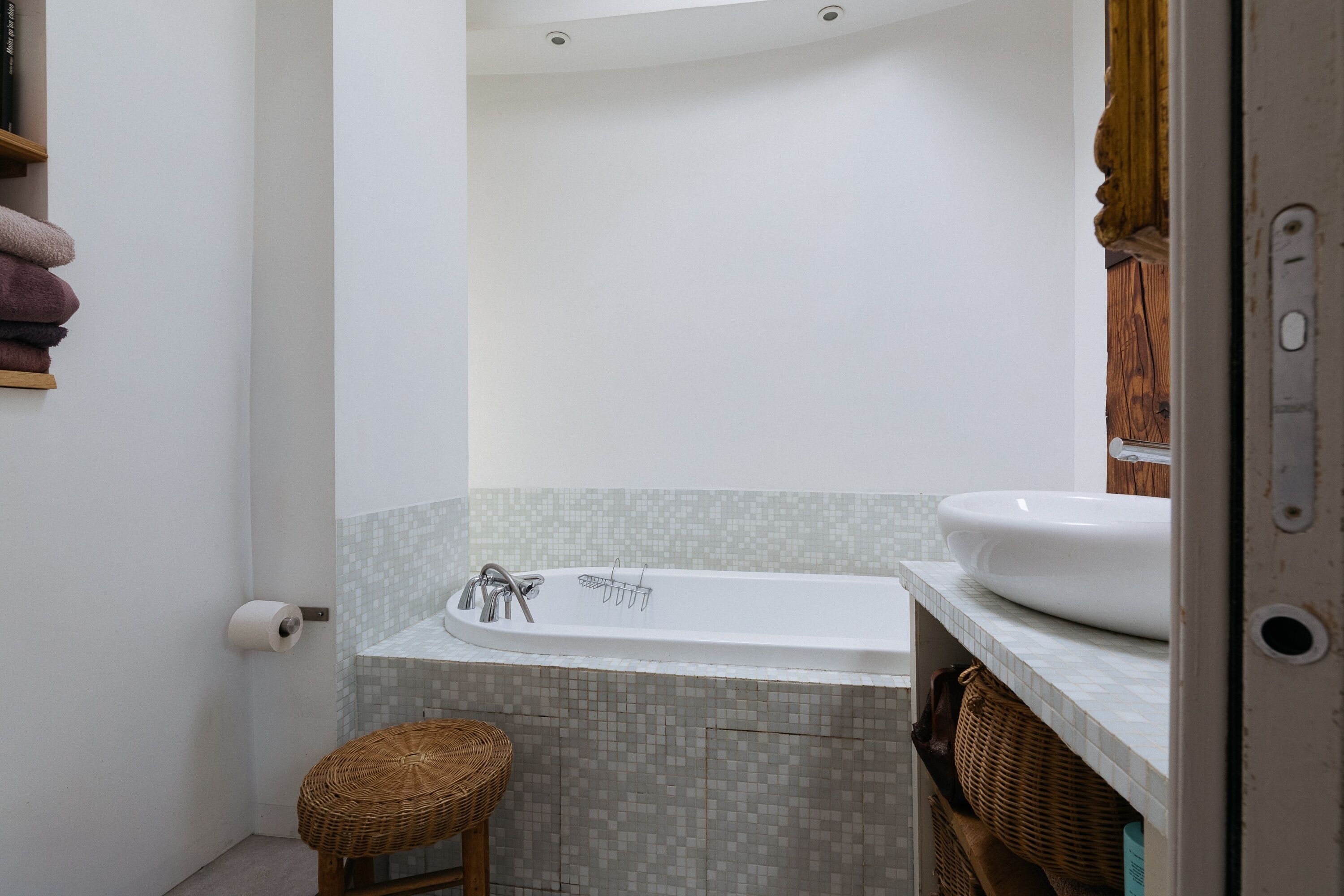 Ein Badezimmer mit einer Badewanne, einem Waschbecken, einer Toilette und einem Korbstuhl.
