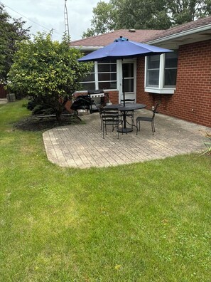 A patio area with a brick patio, a table with chairs, and a blue umbrella. - Brand new listing 1 mile from the quaint villages of Marblehead & Lakeside (Lakeside)