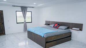 Een moderne slaapkamer met een groot bed, een hoofdeinde, een nachtkastje en een raam met gordijnen.