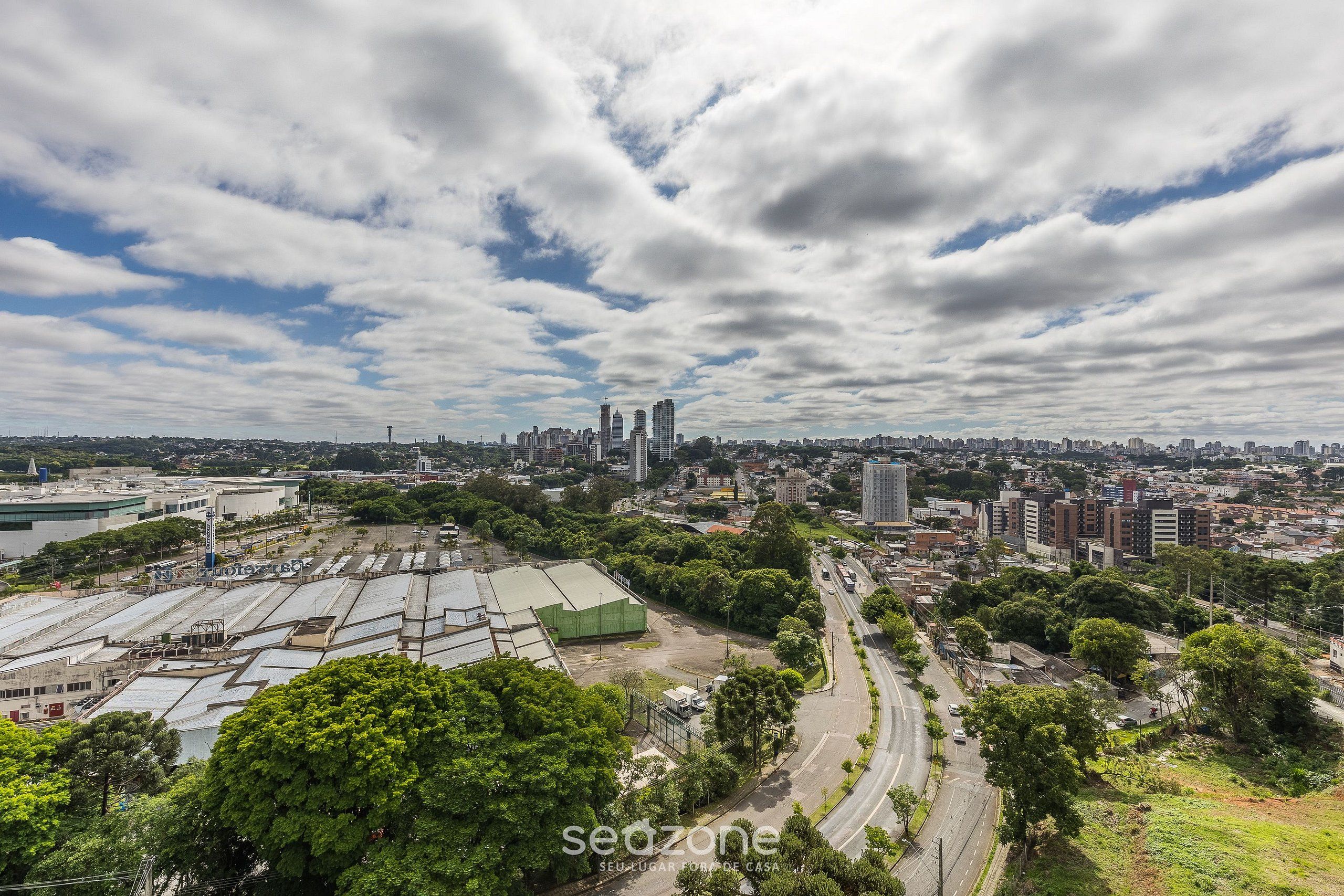 A cityscape with a prominent industrial area, a curved road, and a mix of residential and commercial buildings.