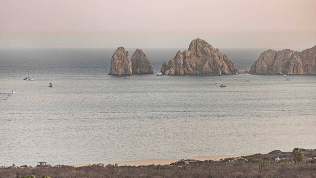 Un paisaje costero con formaciones rocosas y mar tranquilo.