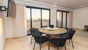 Un comedor con una mesa redonda, sillas negras y un televisor montado en la pared.