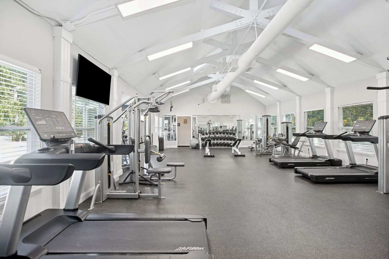 A gym with treadmills, weight machines, and dumbbells.