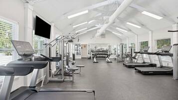 A gym with treadmills, weight machines, and dumbbells.