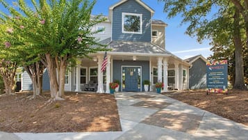 A two-story building with a blue exterior, a covered porch, and an American flag.