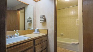 Un bagno con lavandino, specchio, porta asciugamani e zona doccia.