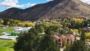 Un quartier résidentiel avec des maisons, un terrain de sport verdoyant et une montagne en arrière-plan.