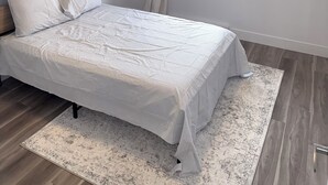 Una camera da letto con un letto, un quadro, una finestra con tende e una lampada a soffitto.