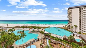 Ein Resort mit Schwimmbad, Strand und einem hohen Gebäude mit Balkonen.