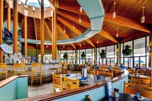 Un restaurant spacieux avec de hauts plafonds, des poutres en bois et de grandes fenêtres.