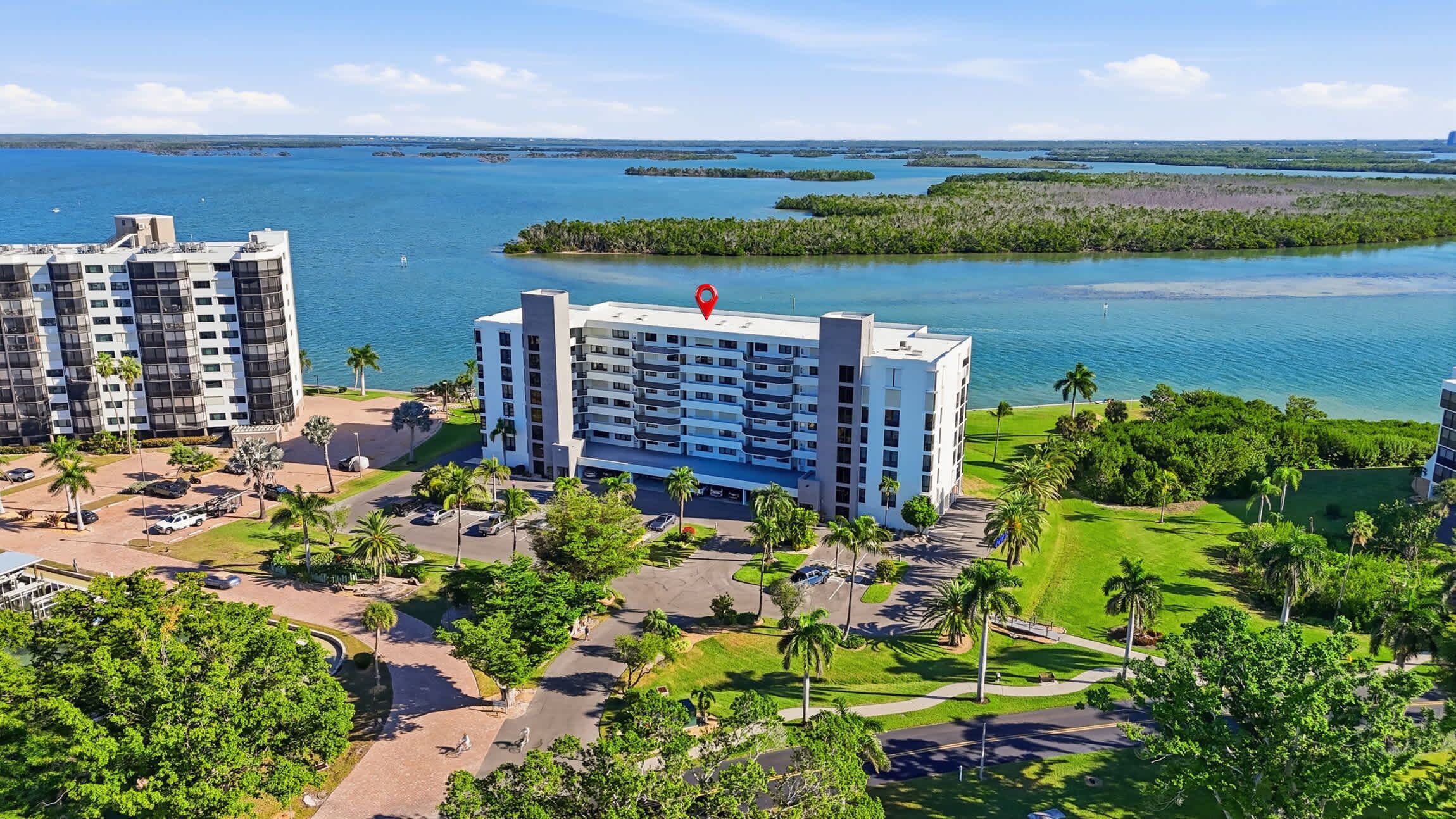 Ein modernes Hotel mit mehreren Etagen, einem Parkplatz und Blick auf das Meer und die Inseln.
