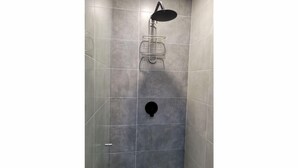 Eine Dusche mit Handbrause und am Wand montiertem Wasserhahn.