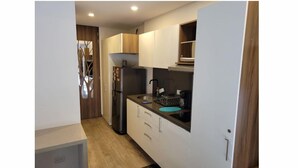 Eine kleine Küche mit Kühlschrank, Spüle und Schränken.