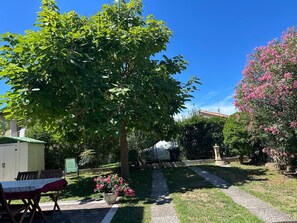 A garden with a paved path, a table with chairs, and a building in the background. - BERTO'S HOUSE2 (TREPORTI)