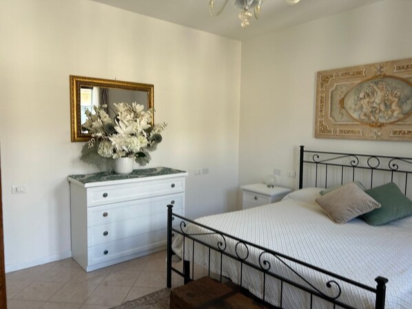 A bedroom with a bed, a dresser, a nightstand, a mirror, and a decorative painting. - BERTO'S HOUSE2 (TREPORTI)