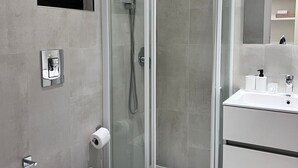 A modern bathroom with a glass-enclosed shower, a toilet, a sink, and a mirror. - Best Stay-Apartments in Andrea da Bari 2 (Bari)