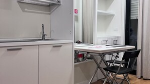 A modern kitchen with white cabinets, a built-in sink, and a dining area with a table and chairs. - Best Stay-Apartments in Andrea da Bari 2 (Bari)