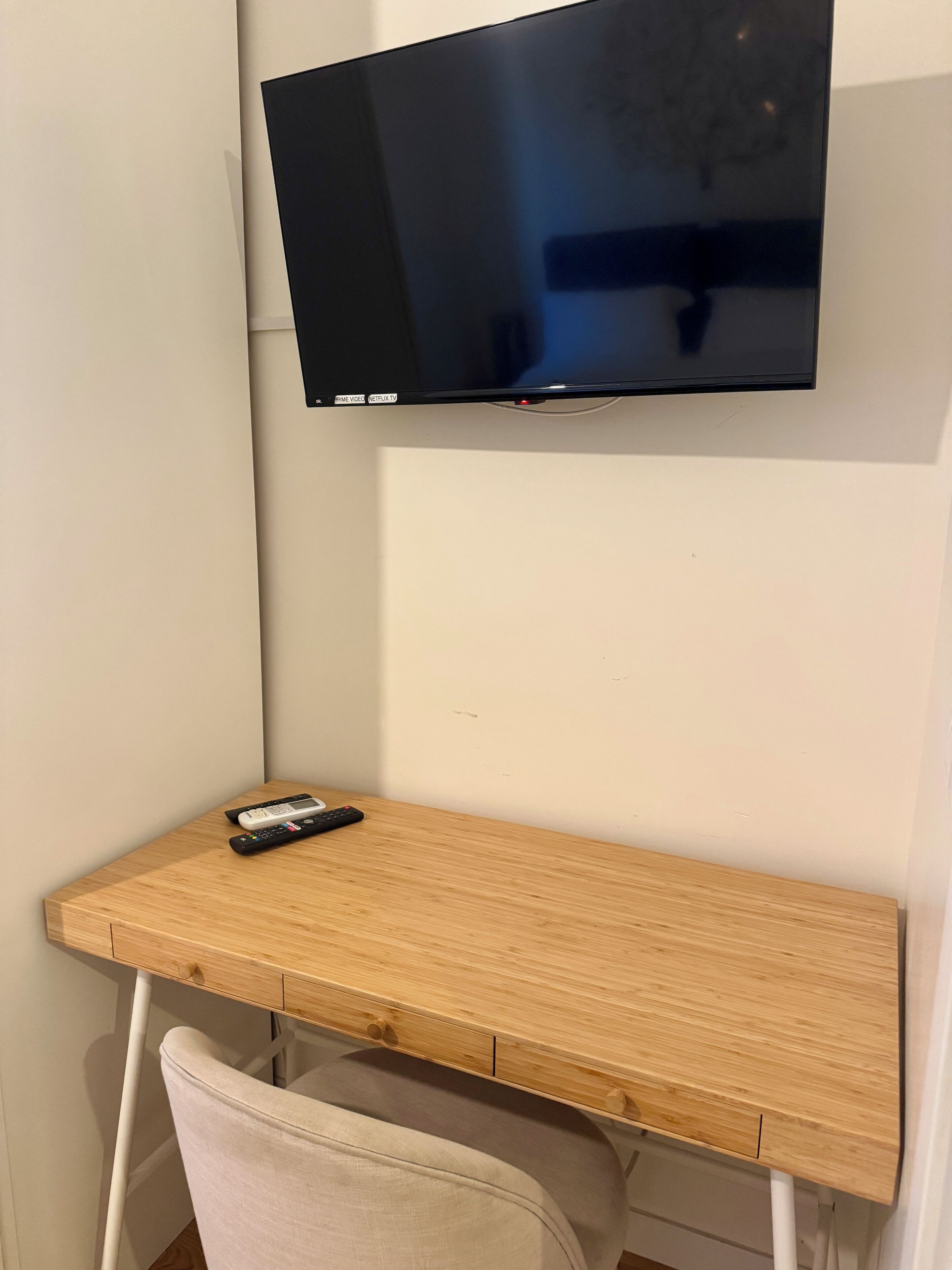 A wooden desk with a television mounted above it.
