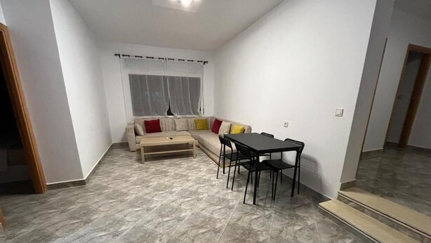 Un salon avec un canapé, une table à manger avec des chaises et une fenêtre avec des rideaux.