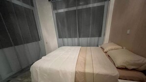 Une chambre à coucher avec un lit, une table de chevet et un rideau.
