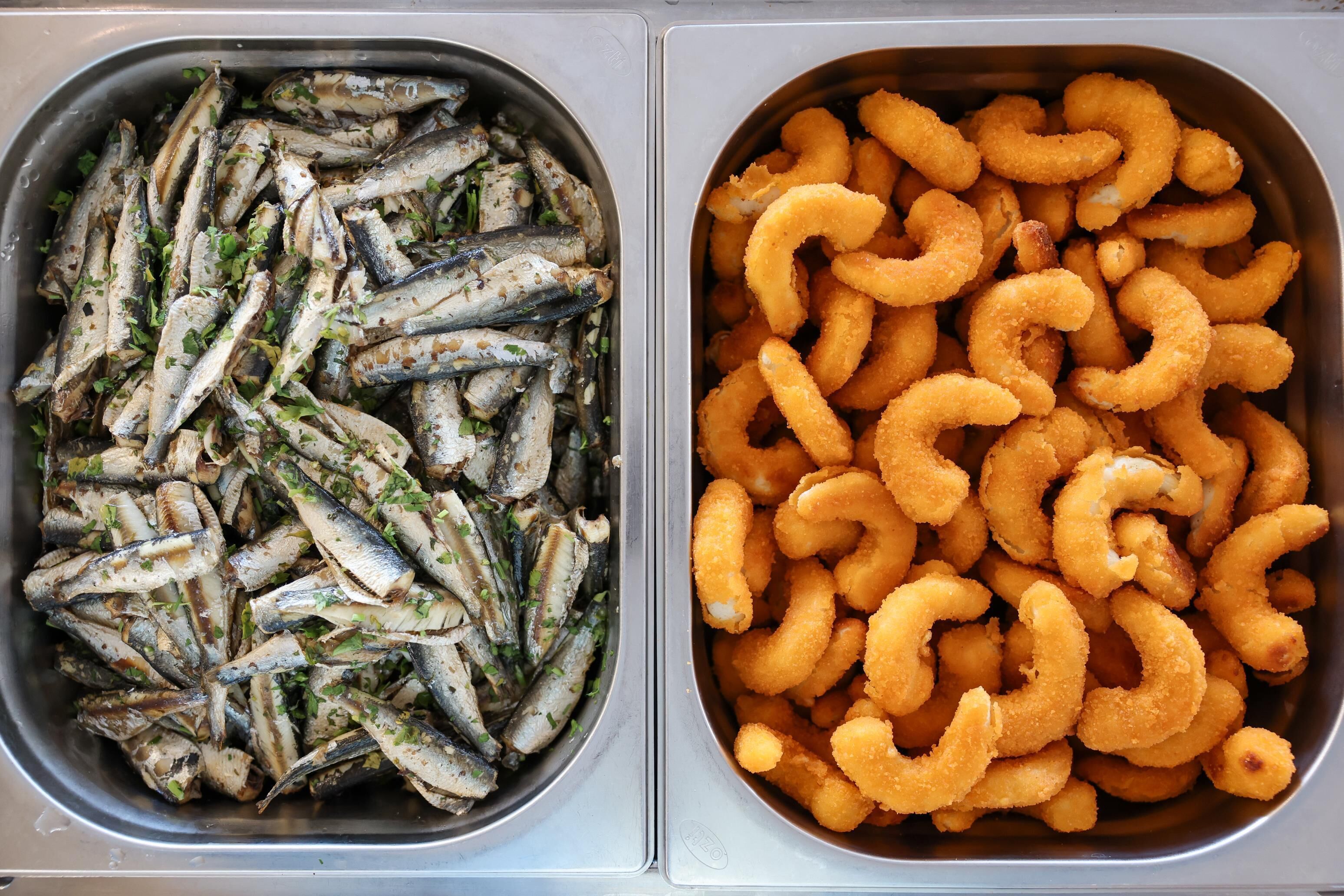 Two metal trays, one with grilled fish and the other with fried calamari.