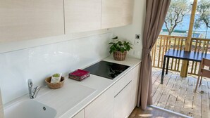 Et moderne køkken med vask, komfur og skabe. Der er et lille bord med en plante og en kurv på bordpladen.