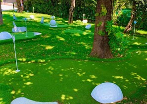 A golf course with neatly mowed grass and several white golf balls placed on the ground.
