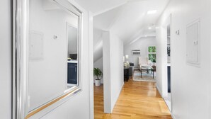 Ein moderner, gut beleuchteter Korridor mit Holzboden, der zum Küchenbereich führt.