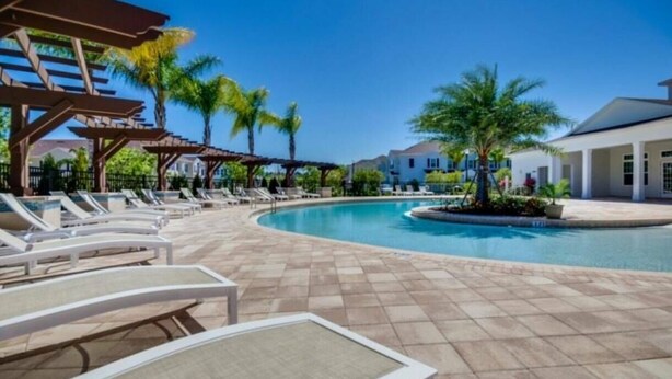 A pool area with lounge chairs and a pergola. - 4BR Townhome Near Disney at Lucaya Village (Kissimmee)