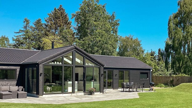 Ein modernes Haus mit Terrasse, großen Fenstern und einem Rasen.