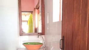 A bathroom with a white sink, a green and orange basin, a mirror, and a wooden door. - POSADA EL ARTESANO DE RAQUIRA (Ráquira)