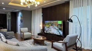 A modern living room with a large L-shaped sectional sofa, a coffee table, and a flat-screen TV. - 3 Bedroom En-Suite, Wi-Fi, Secured, 24/7 Power (Lagos)