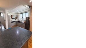 A modern kitchen with a granite countertop, wooden cabinets, and a large window providing a view of the city. - 3 Bedroom En-Suite, Wi-Fi, Secured, 24/7 Power (Lagos)