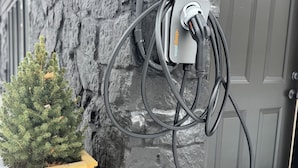 Une borne de recharge fixée à un mur en pierre, à côté d’une porte.