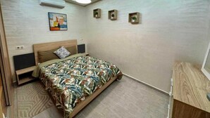 A modern bedroom with a bed, a ceiling light, and a wall-mounted air conditioner. - Gueliz Twin Balcony Apartment F3 (Marrakesh)