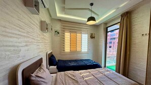 A bedroom with a bed, a bedside table, a window with blinds, and a view of the outside. - Gueliz Twin Balcony Apartment F3 (Marrakesh)